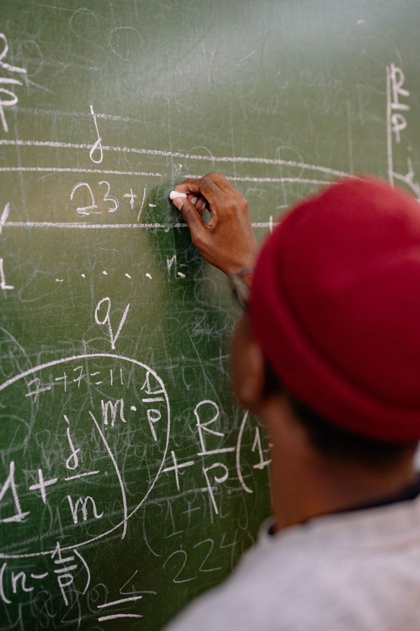 Math work being explained on a classroom chalkboard